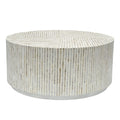 Round drum coffee table covered in vertical mother of pearl mosaic tiles in white and cream tones, straight on view against