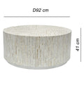 Side view of round drum coffee table fully clad in vertical white and beige mother of pearl mosaic tiles with a low metal