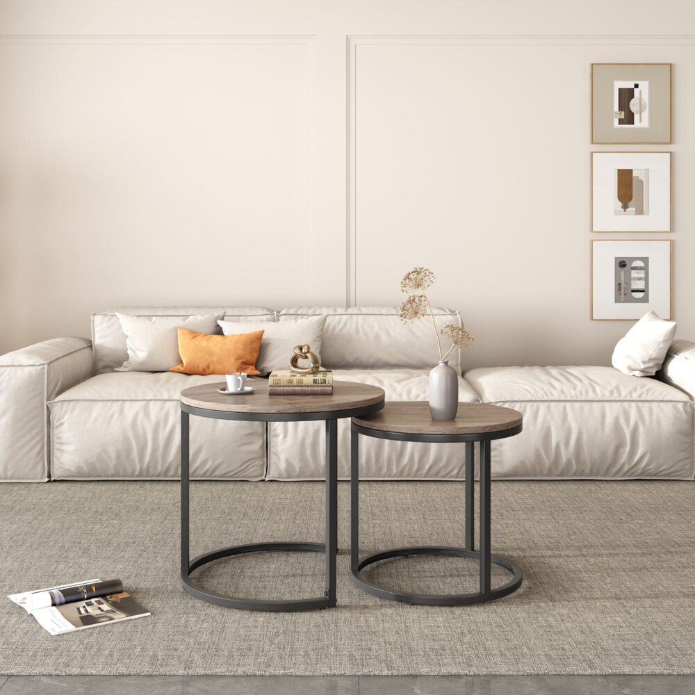 Two round nesting coffee tables with walnut-look tops and dark metal bases in front of cream sofa, framed art on wall