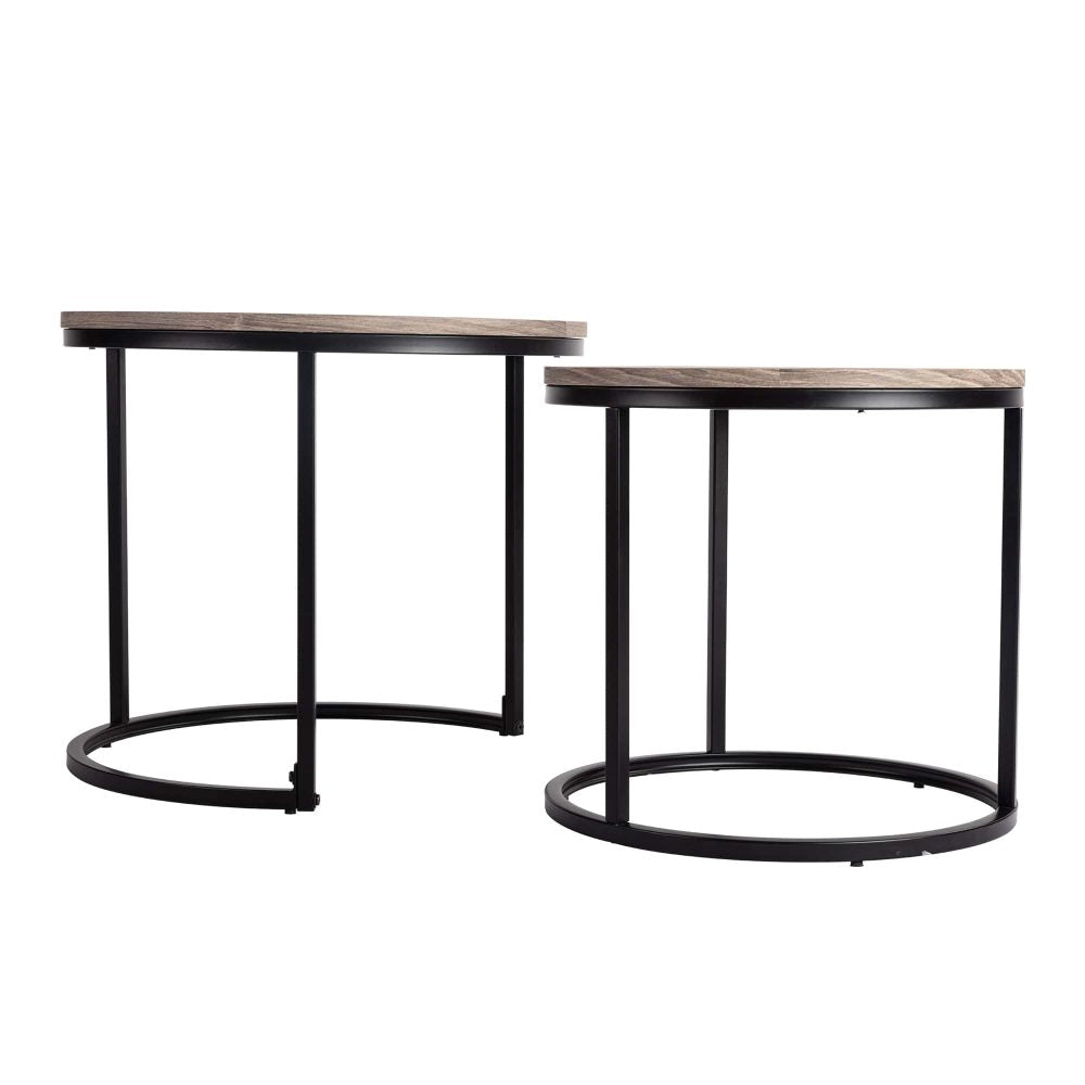 Two round nesting coffee tables with grey-tone wood tops and black ring bases viewed from the side on white background