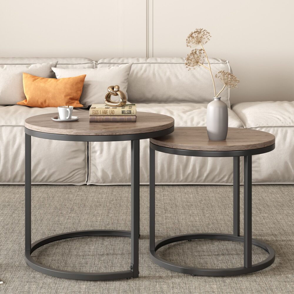Two round nesting coffee tables with walnut-look tops and dark metal bases in front of cream sofa, framed art on wall