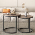 Two round nesting coffee tables with walnut-tone tops and black circular metal bases in living room setting