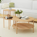Round oak two-tier coffee table and matching side table with a vase of flowers and books in front of a white sofa on a cream