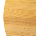 Macro close-up of natural pine circular table top surface showing light wood grain, knot lines and two-tone timber joint