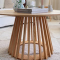 Round natural pine coffee table with slatted flared pedestal base, close-up view showing base construction and books on top