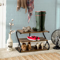Rustic 3-tier industrial shoe rack in hallway with boots and shoes on all shelves against blue brick wall