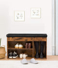 Rustic wood shoe bench in hallway with boots and shoes stored, wicker basket nearby, framed artwork on wall
