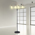 Four-arm industrial floor lamp with lit Edison bulbs in a minimal modern room with frosted glass panels