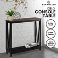 Sarantino Cielo console table, dark walnut finish and black X-frame, styled in brick room, badges: 2-Tier Shelf, Sleek Design
