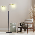 Dual-arm LED floor lamp lit in a beige room beside a ceramic stool, wooden armchair with throw and pampas grass