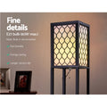 Close-up of black lattice shelf floor lamp shade glowing warm with E27 60W max bulb spec and feature text overlay
