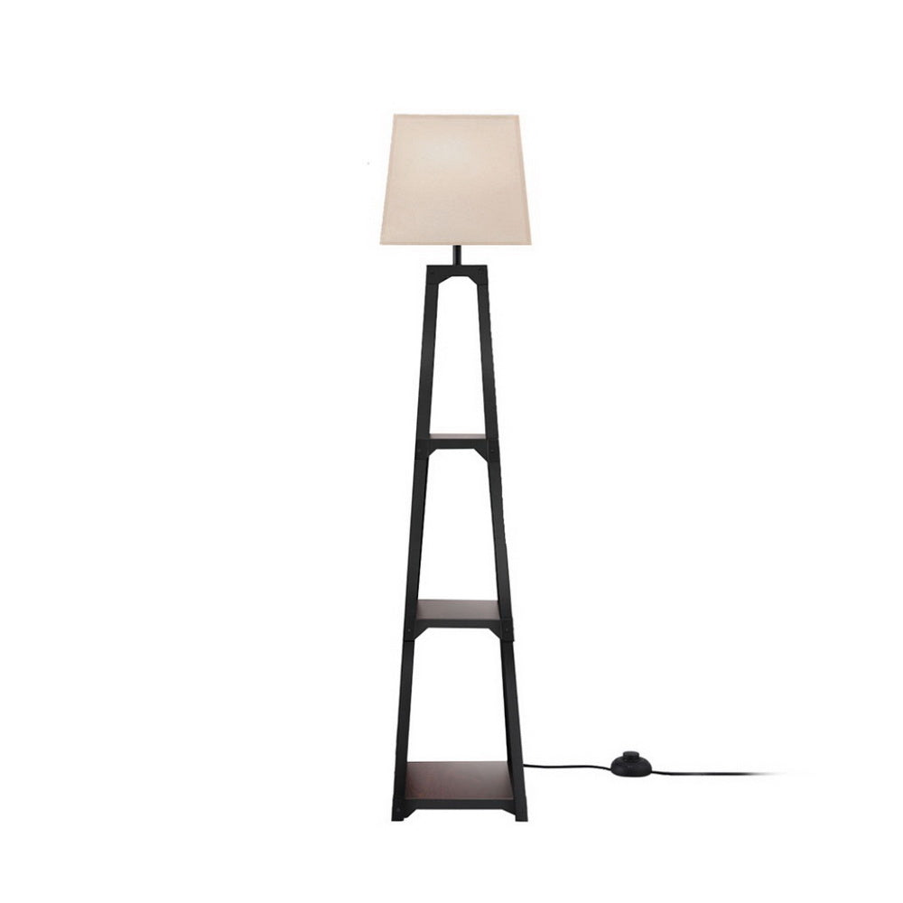 Floor lamp with beige empire shade on tapered black open-frame base with two shelves on white background