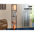 Brown fabric shelf floor lamp in living room with books and orange vase on shelves, text overlay floor lamp with 3 shelves