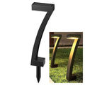 Black arch solar garden light on white background with spike stake base, inset shows two units glowing warm on grass at night