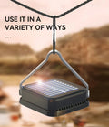 Square solar camping light hanging from rope via triangular metal hanger outdoors, text Use It In A Variety Of Ways
