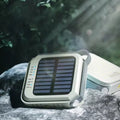 Solar camping light back view showing solar panel with battery level and colour temp LED indicators, placed on outdoor rocks