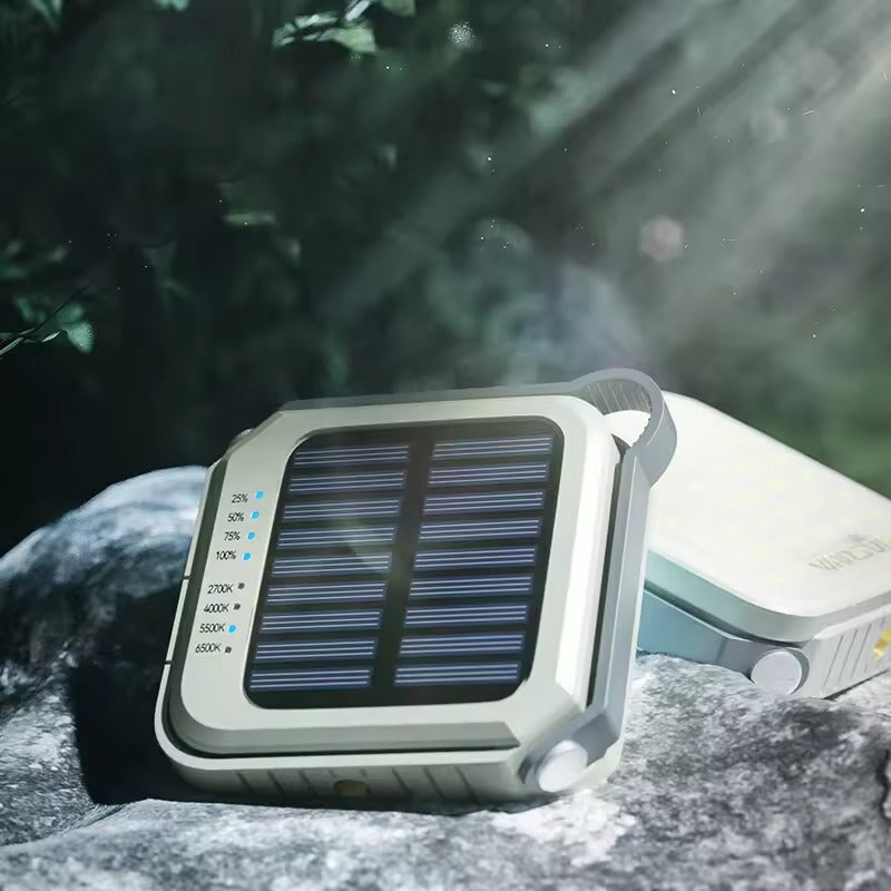Solar camping light back view showing solar panel with battery level and colour temp LED indicators, placed on outdoor rocks