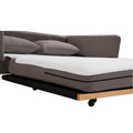 Close-up of taupe fabric sofa bed partially extended showing white mattress foot and casters on wood base