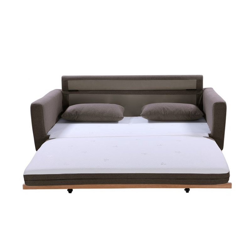 Taupe fabric sofa bed fully extended showing white mattress, two scatter pillows and wood frame with casters