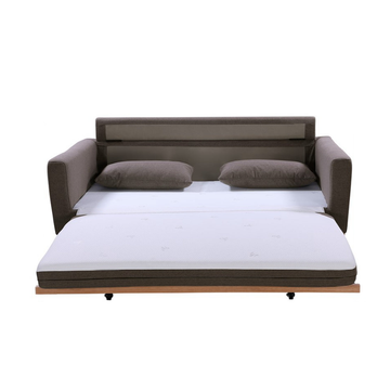 Taupe fabric sofa bed fully extended showing white mattress, two scatter pillows and wood frame with casters