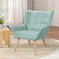 Teal green grid-tufted armchair with wood legs in living room with sheer curtains, wooden side table and area rug