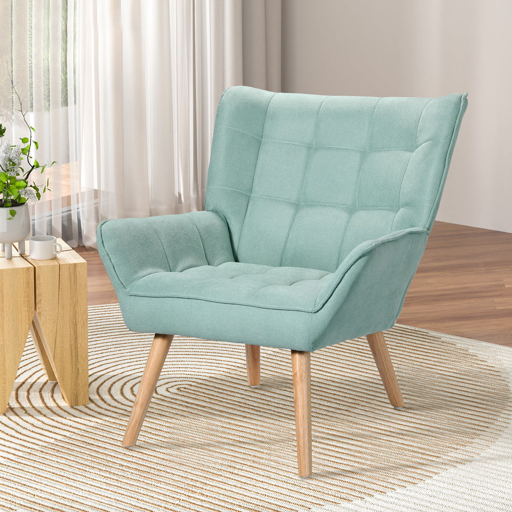 Teal green grid-tufted armchair with wood legs in living room with sheer curtains, wooden side table and area rug