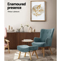 Teal velvet wingback armchair and footstool in room with slat sideboard and framed botanical art, 