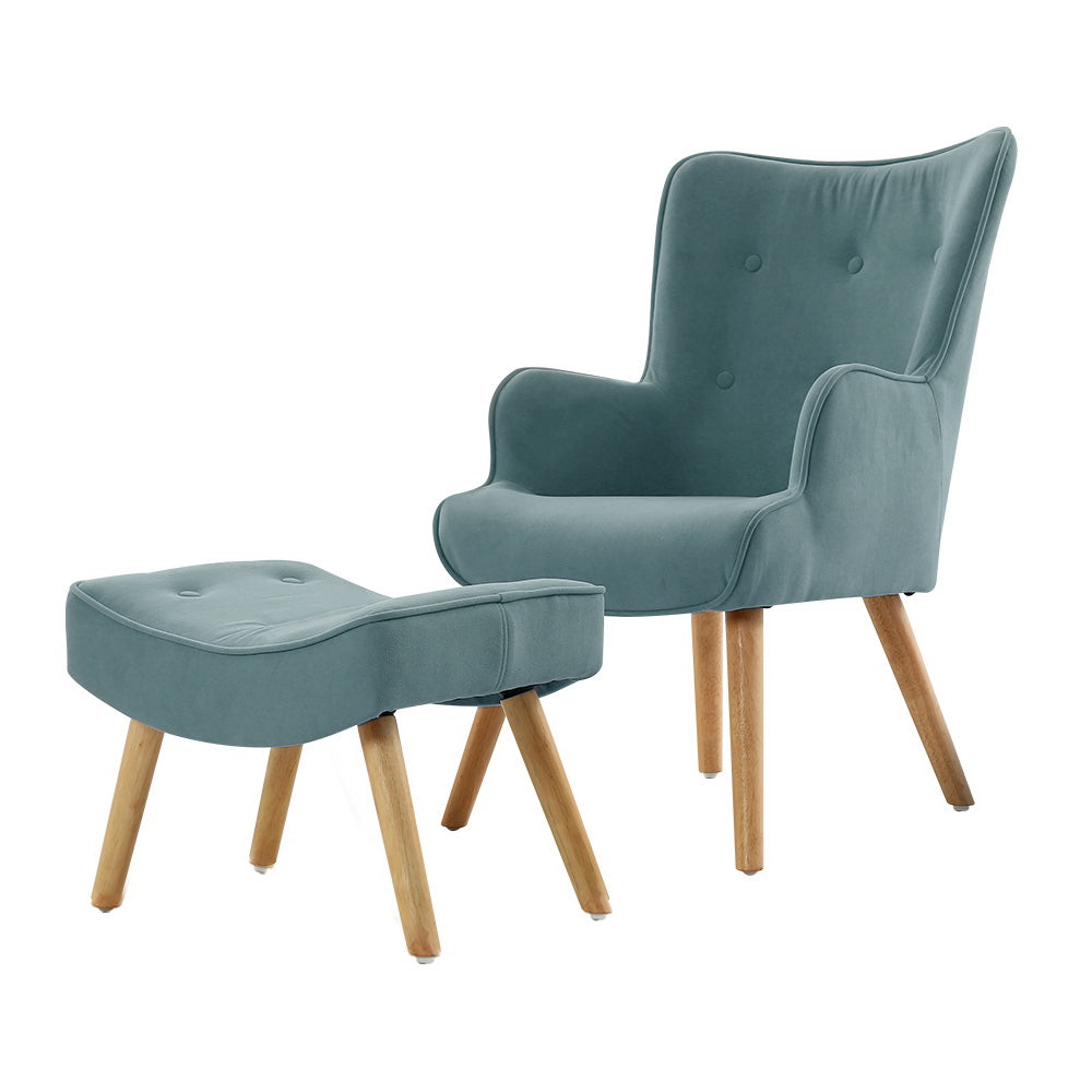 Teal velvet button-tufted wingback armchair with footstool and natural wood legs, three-quarter view, white background