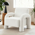 White teddy fabric armchair with arched arms and cylindrical legs in bright room with plants and black dome lamp