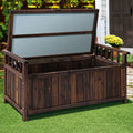Dark timber storage bench with lid open in garden, house door and yellow flowers visible in background