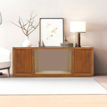 Walnut TV console with two reeded doors flanking open central bay in living room, vase, art and lamp on top, sofa beside