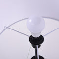 Interior view of tripod floor lamp shade showing white globe bulb in black socket with wire shade frame