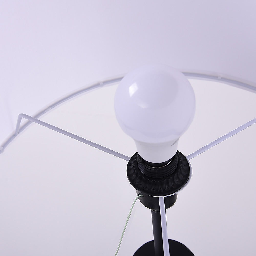 Interior view of tripod floor lamp shade showing white globe bulb in black socket with wire shade frame