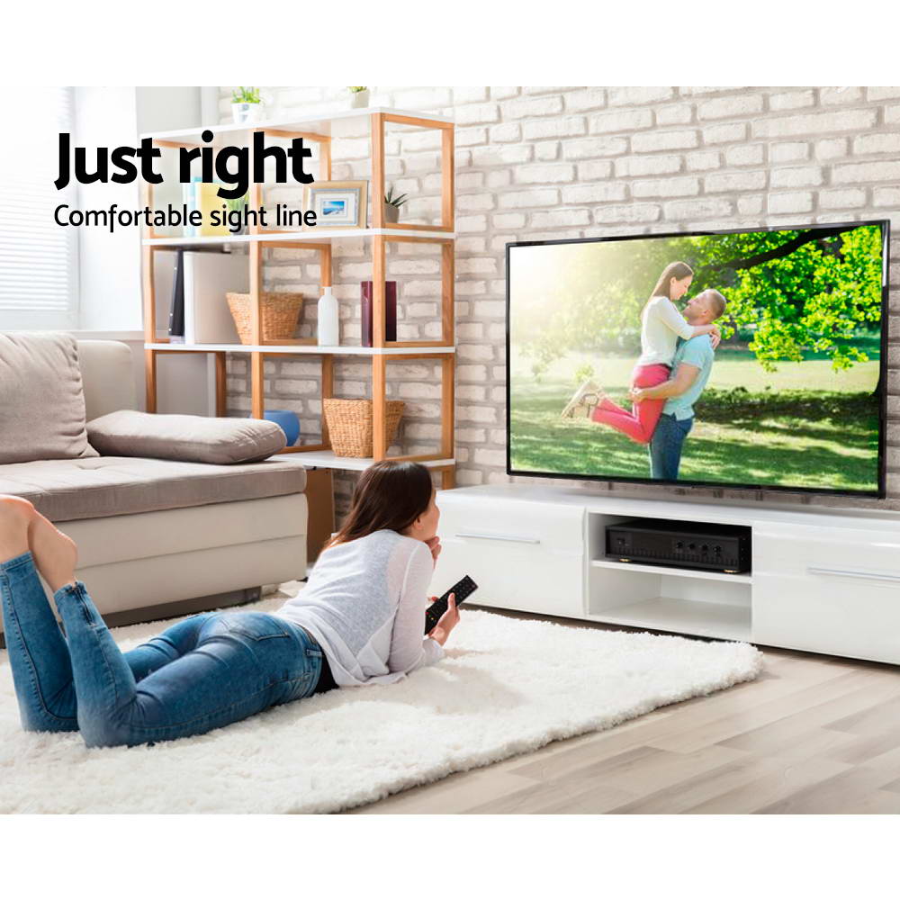 TV wall bracket comfortable sight line lifestyle woman lying on white rug watching TV on white brick wall oak bookshelf