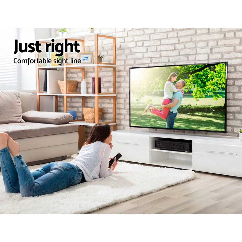 TV wall bracket sight line lifestyle woman lying on white rug watching TV on white brick wall with oak bookshelf
