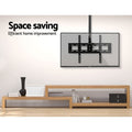 TV ceiling mount space saving lifestyle with transparent TV mounted from ceiling above oak TV unit in beige room