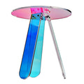 Round iridescent acrylic side table viewed from above at an angle showing yellow-to-blue gradient tabletop and teal leg on a