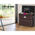 Walnut shoe bench lid lifted open showing hidden footwear accessories inside lifestyle with large window and deck view