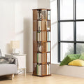 Walnut-finish slat rotating tower bookshelf filled with books in living room near large window, sofa and lamp visible