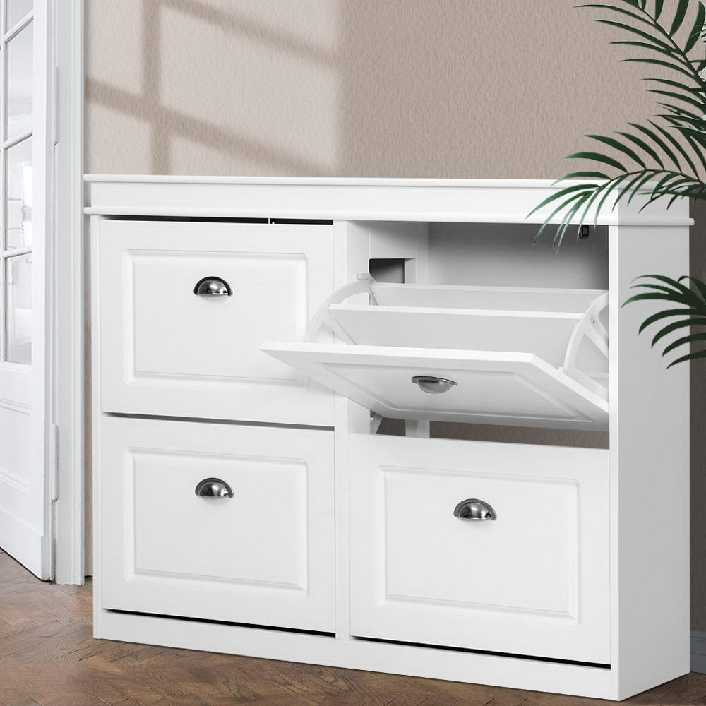 White wide four-door shoe cabinet top-right flip-out tray open showing mechanism in hallway with palm plant and natural light
