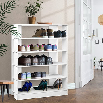 White 5-tier shoe rack loaded with sneakers leather shoes and sequin heels in hallway herringbone floor palm plant and door