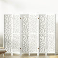 White 6-panel geometric MDF room divider with star pattern cutouts in lifestyle room with chair and ottomans