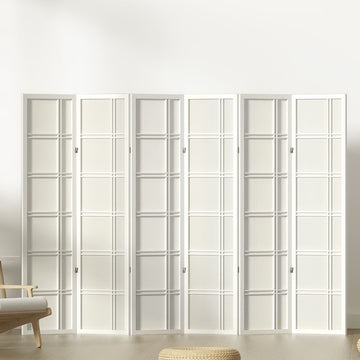 White 6-panel grid pattern shoji room divider in lifestyle room against white wall with wooden chair and floor cushion