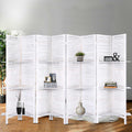 White 6-panel louvered wood room divider with 3-tier shelves in lifestyle room with plant vases and books on shelves