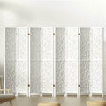 White 8-panel MDF room divider with geometric star pattern cutouts in lifestyle room with chair and ottomans