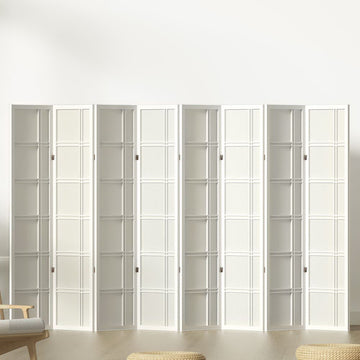 White 8-panel grid pattern shoji room divider in lifestyle room against white wall with chair and floor cushions