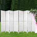 White 8-panel louvered wood room divider in outdoor garden with green lawn and pink floral arch drapery overhead