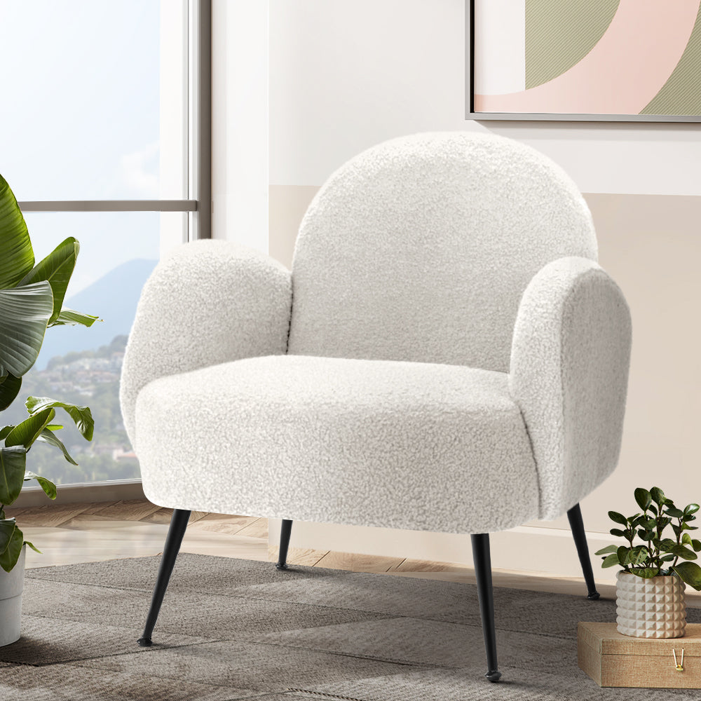 White boucle armchair near window with mountain view, tropical plant and abstract wall art in living room