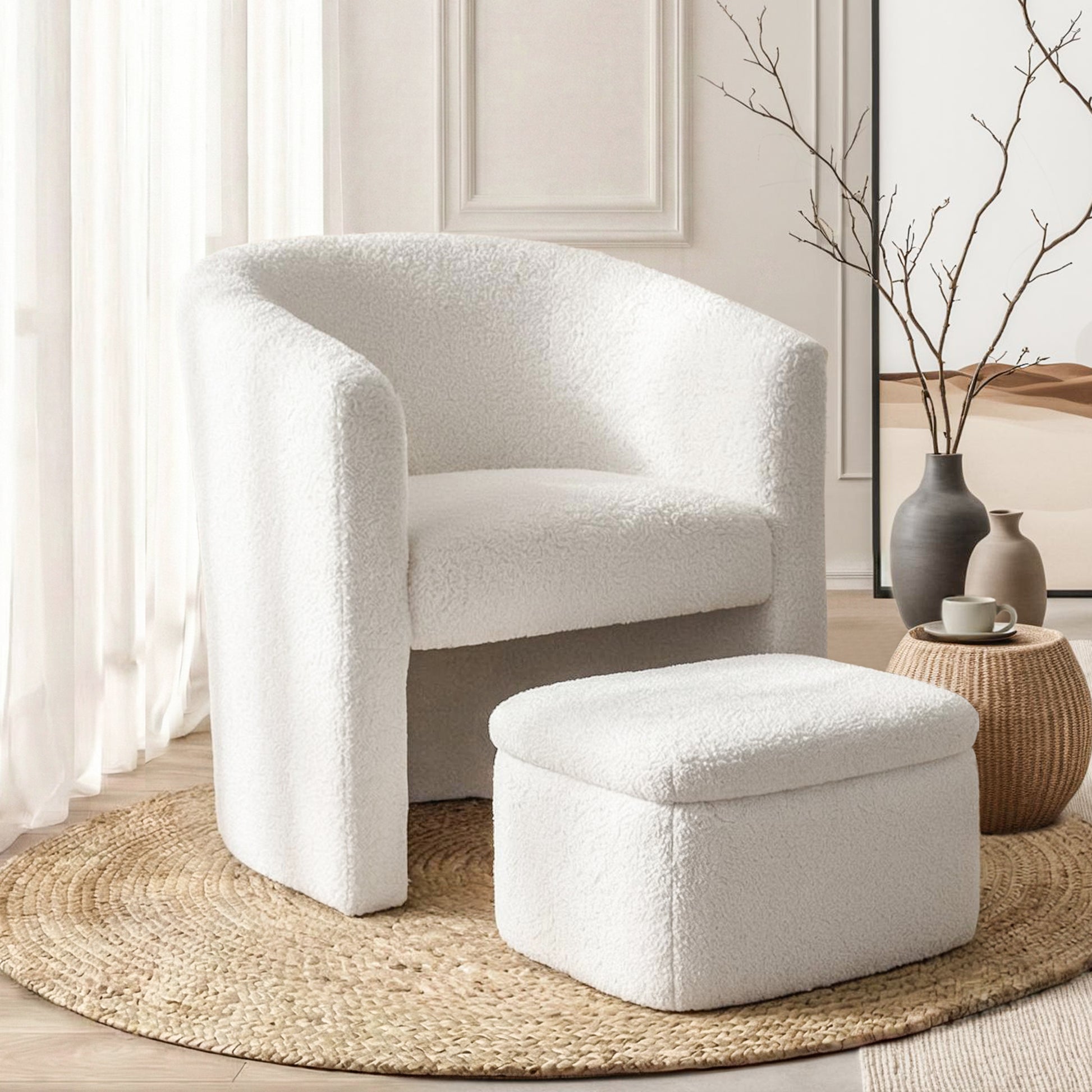 White boucle barrel accent chair with matching square ottoman on round jute rug, curtains and branch vases in background