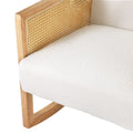 Close-up of white boucle rocking chair showing wood frame with woven rattan cane armrest and boucle seat cushion